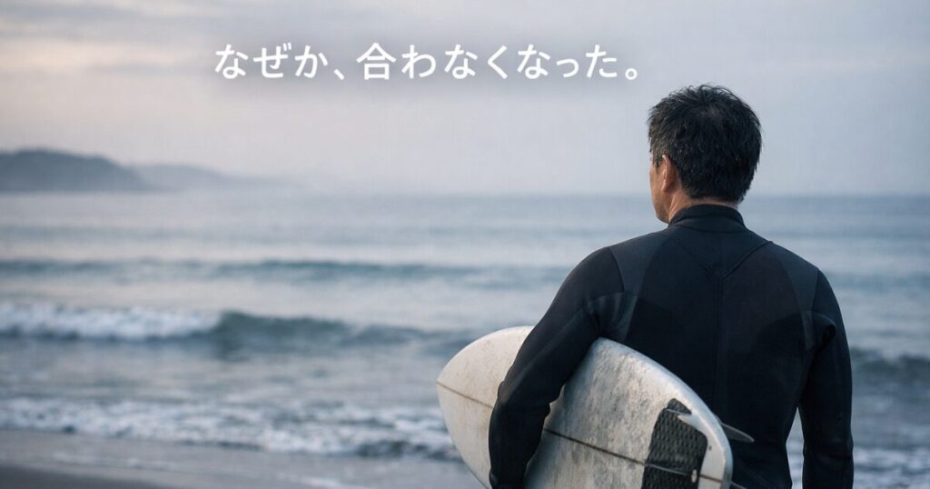 海を見つめるミドル世代サーファーの後ろ姿。40〜50代がサーフボード選びに迷う心境を表したイメージ。