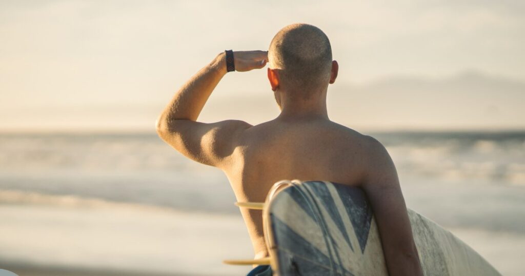 海の様子を見つめるサーファーの後ろ姿、テイクオフ時の心理的ブレーキを表すイメージ。