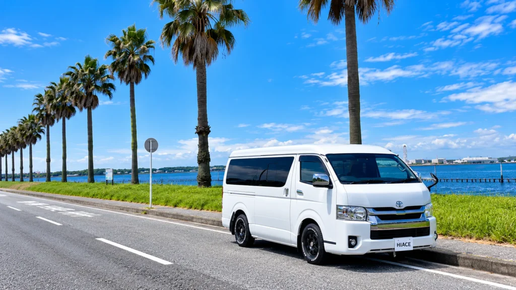 ヤシの木が並ぶ海沿いに駐車したハイエースワイドバン
